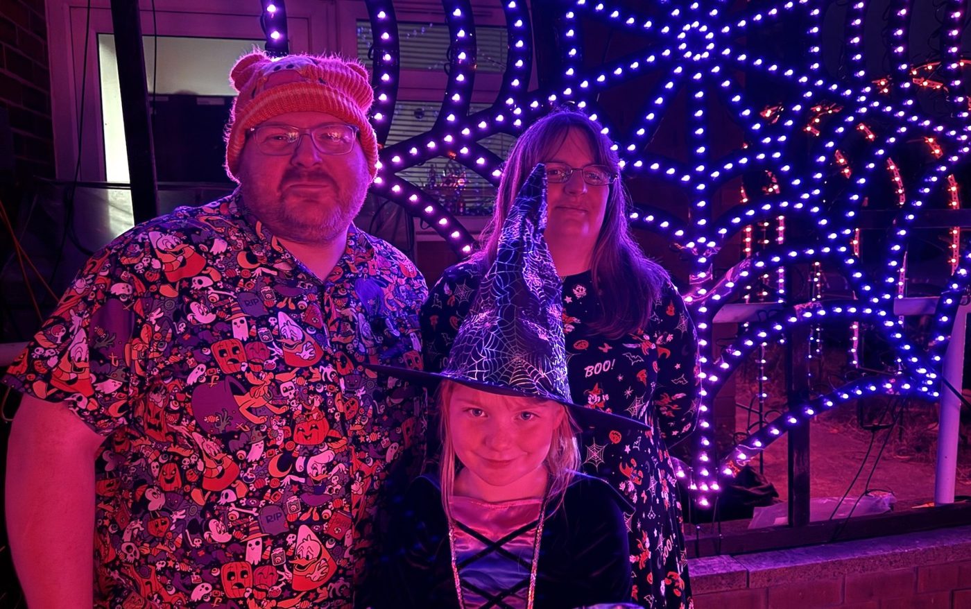 The Hodgson family dressed up for Halloween in front of a giant web of lights