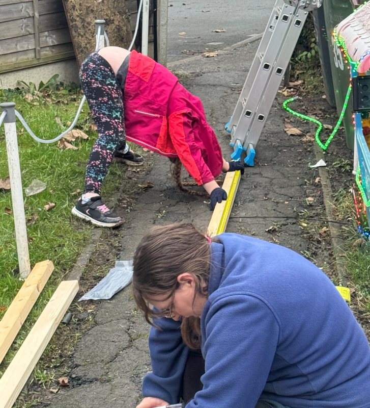 Scarlett ‘helping’ with the build by holding a piece of wood, while her mum measures and marks it